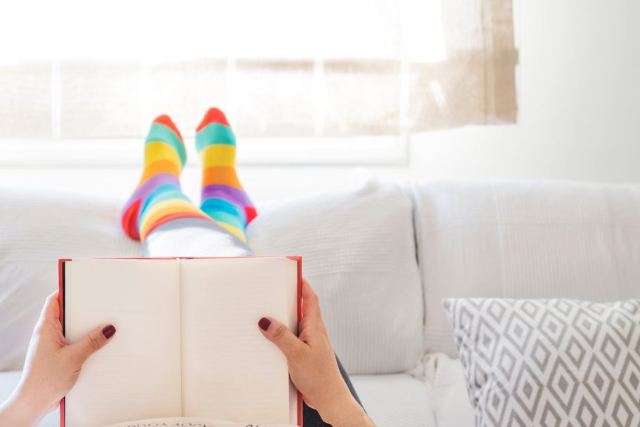 Lesbian Woman Relaxing At Home On A Sofa Reading A Book And Dres